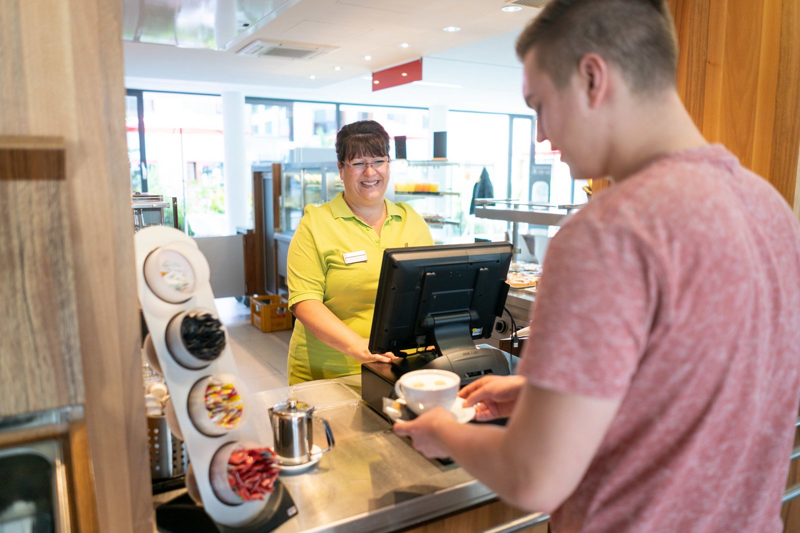 Besucher bestellt eine Tasse Kaffee in der Cafeteria